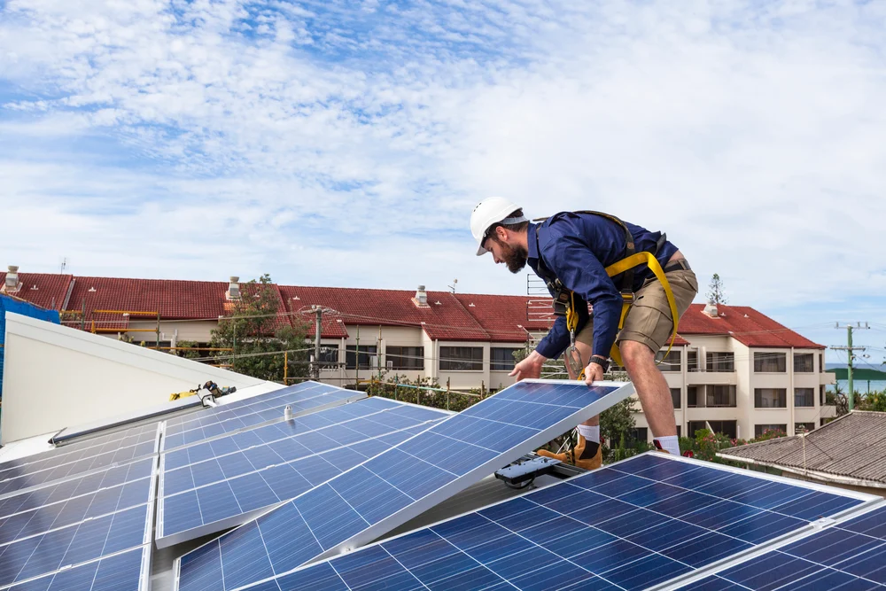Solar panel technician installing solar panels on roof